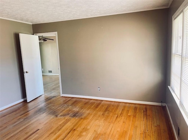 spare room with baseboards, a textured ceiling, light wood-style flooring, and crown molding