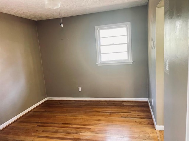 unfurnished room featuring baseboards, a textured ceiling, and hardwood / wood-style floors