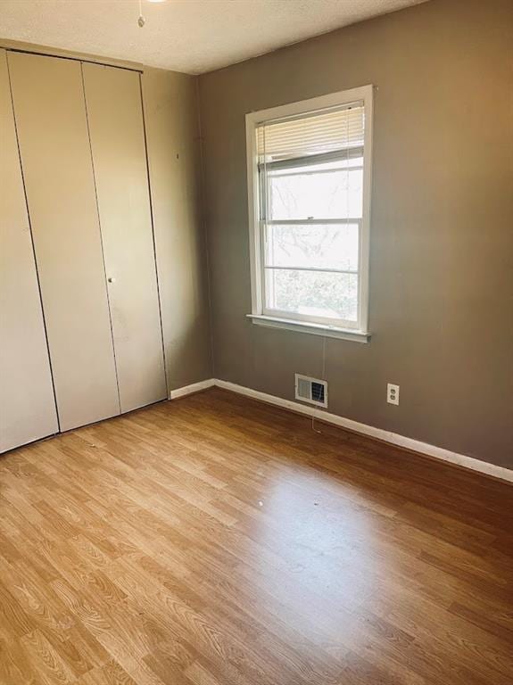 unfurnished bedroom featuring a closet, visible vents, baseboards, and light wood-style floors