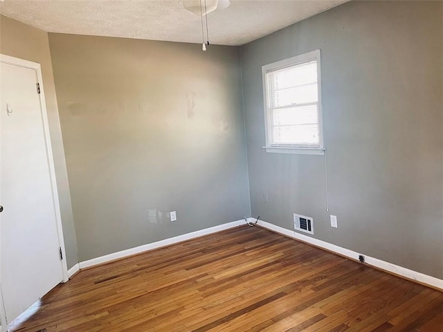 unfurnished room featuring visible vents, baseboards, a textured ceiling, and hardwood / wood-style flooring
