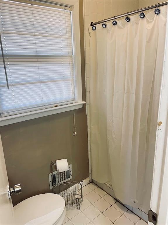 bathroom with a shower with curtain, tile patterned floors, and toilet