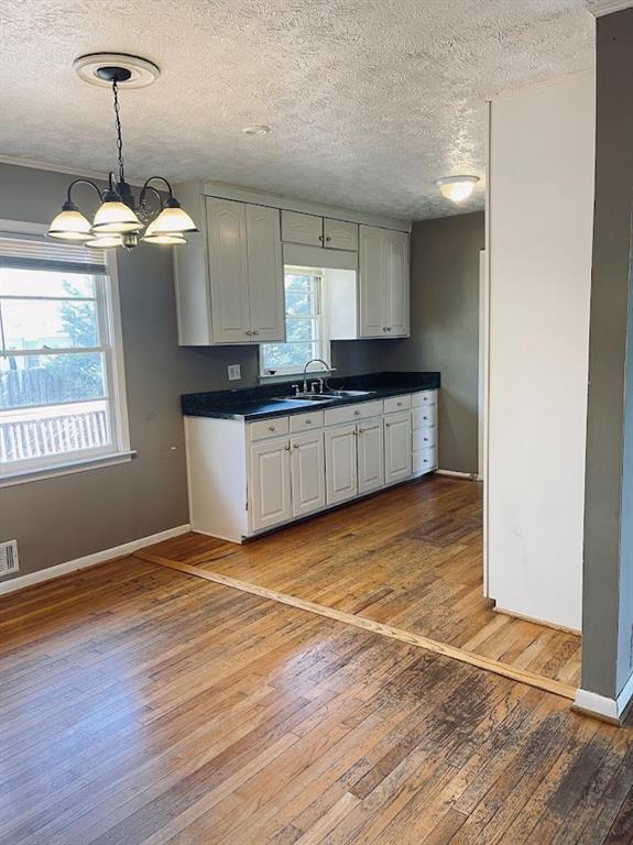 kitchen with dark countertops, plenty of natural light, light wood-style floors, and a sink