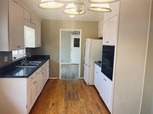 kitchen featuring a sink, white cabinetry, freestanding refrigerator, and oven