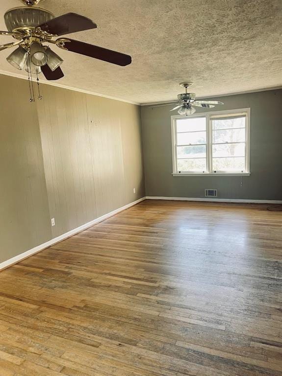 unfurnished room featuring wood finished floors, a ceiling fan, visible vents, and a textured ceiling