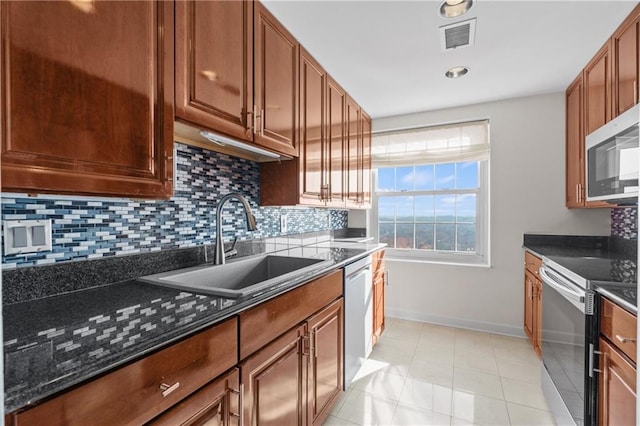 kitchen featuring baseboards, visible vents, a sink, stainless steel appliances, and backsplash