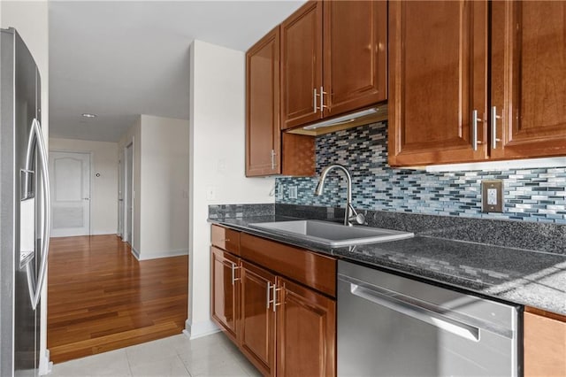 kitchen with a sink, brown cabinetry, tasteful backsplash, and stainless steel appliances