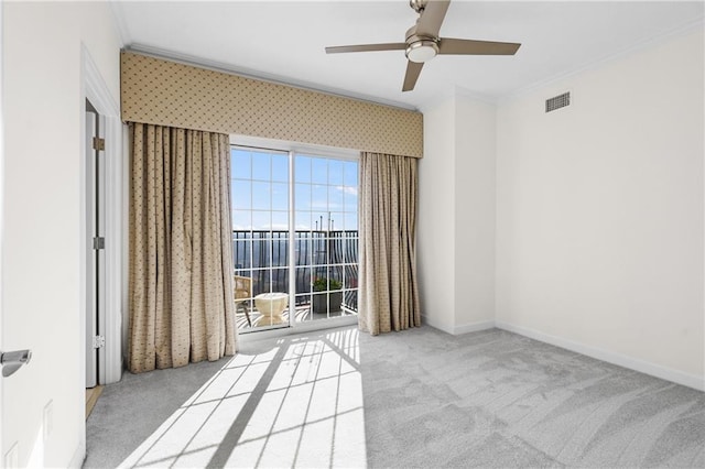 carpeted empty room with visible vents, a ceiling fan, crown molding, wallpapered walls, and baseboards