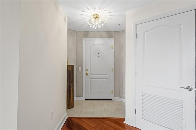 hall with a chandelier, baseboards, and wood finished floors