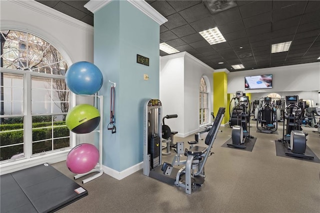 exercise room with crown molding, a paneled ceiling, and baseboards