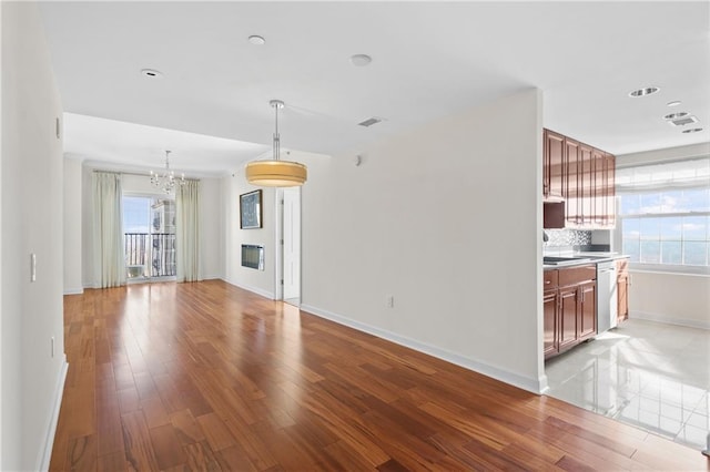 unfurnished living room with a chandelier, visible vents, baseboards, and light wood-style floors