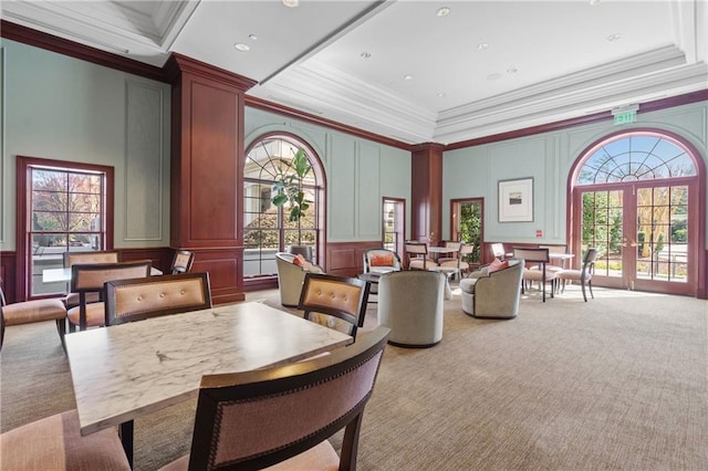 dining room with carpet, ornamental molding, french doors, a high ceiling, and a decorative wall