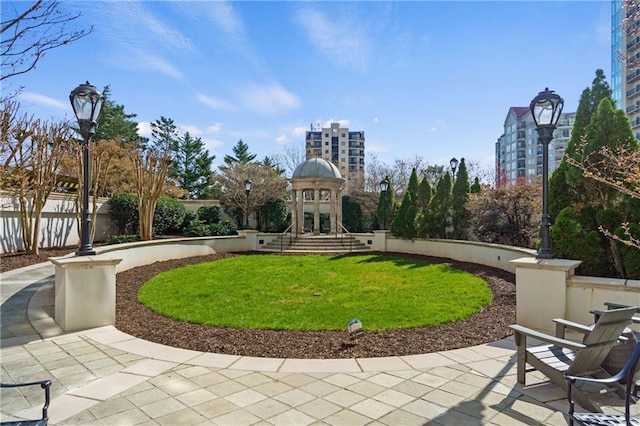 view of home's community with a view of city, a lawn, and fence