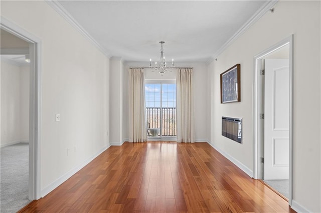 spare room with baseboards, an inviting chandelier, wood finished floors, and crown molding