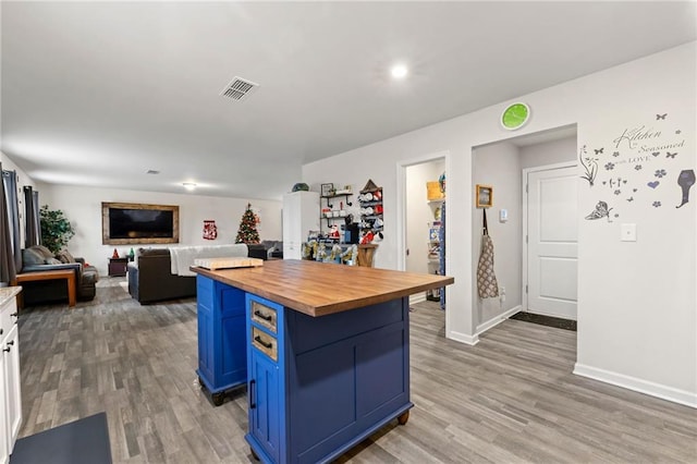 kitchen with butcher block countertops, white cabinets, blue cabinets, and hardwood / wood-style flooring