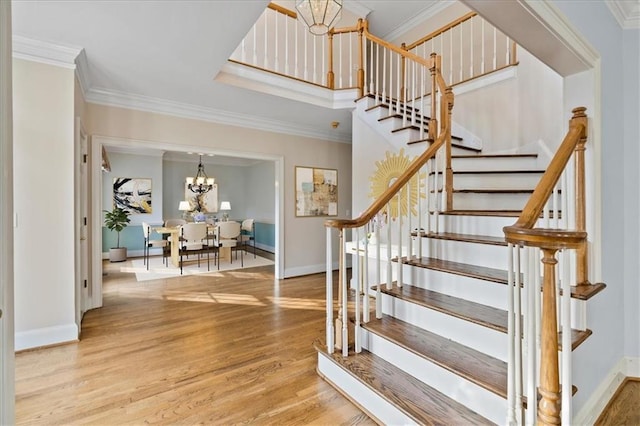 stairs featuring hardwood / wood-style floors, ornamental molding, and a chandelier