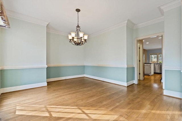 unfurnished room with hardwood / wood-style floors, an inviting chandelier, and ornamental molding