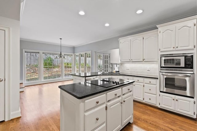 kitchen with black electric stovetop, stainless steel oven, white cabinets, and a kitchen island