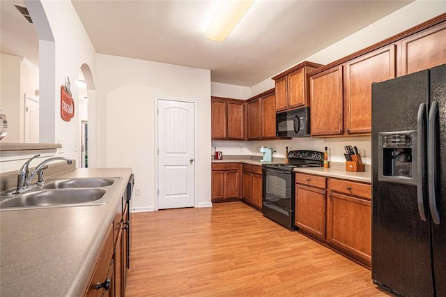 kitchen featuring sink, light hardwood / wood-style floors, and black appliances