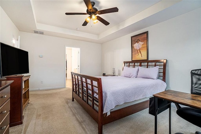 carpeted bedroom featuring a raised ceiling and ceiling fan