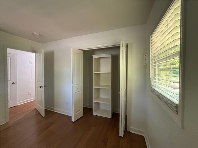 unfurnished bedroom with baseboards and dark wood finished floors