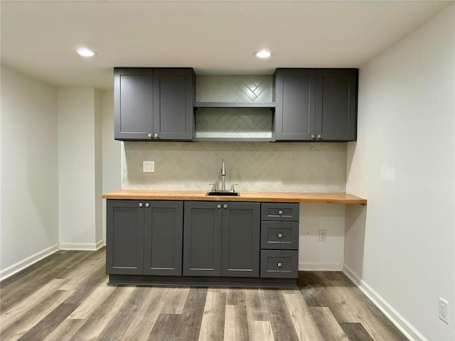 kitchen featuring backsplash, butcher block counters, gray cabinetry, and a sink