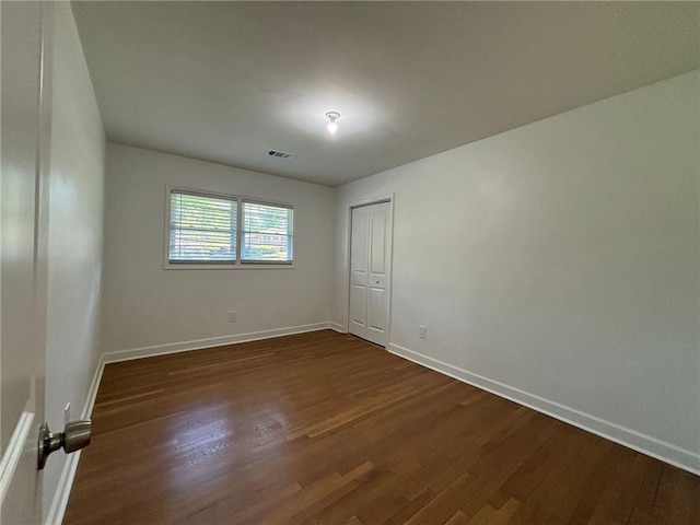 unfurnished room featuring visible vents, baseboards, and dark wood-style flooring