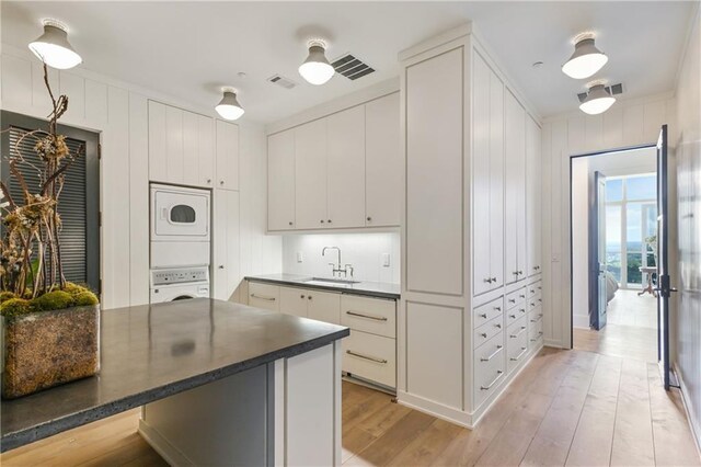 3630 Peachtree Rd NE Unit 3302, Atlanta, GA 30326 - kitchen with visible vents, dark countertops, stacked washing maching and dryer, a sink, and white cabinets
