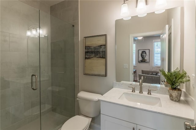 bathroom featuring vanity, a shower stall, and toilet