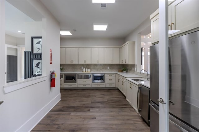 kitchen featuring stainless steel appliances, backsplash, a sink, and light countertops