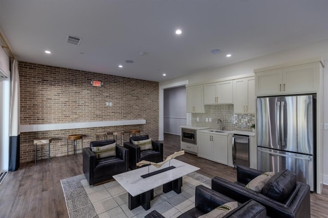 living room with brick wall, wood finished floors, visible vents, and recessed lighting