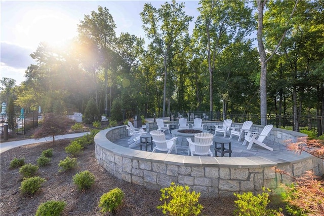 view of community with a fire pit, a patio area, and fence