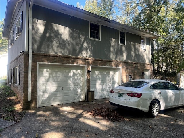 view of side of home with a garage, brick siding, and driveway