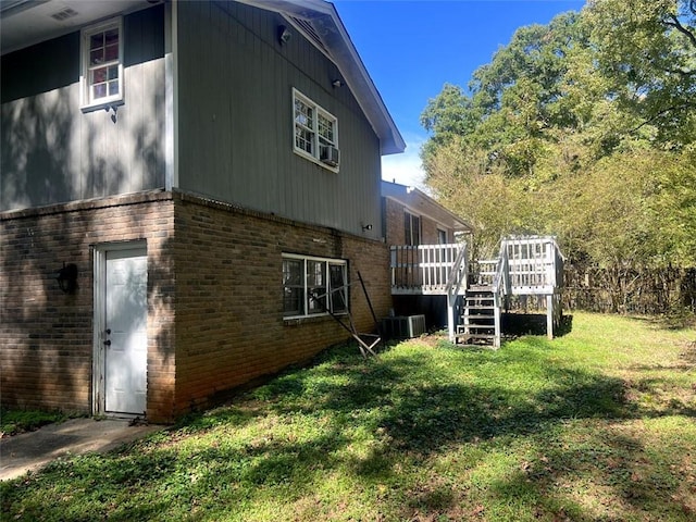 view of property exterior featuring a wooden deck, central AC, a lawn, and brick siding