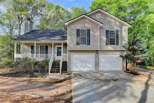 tri-level home with a garage, a porch, a chimney, and concrete driveway