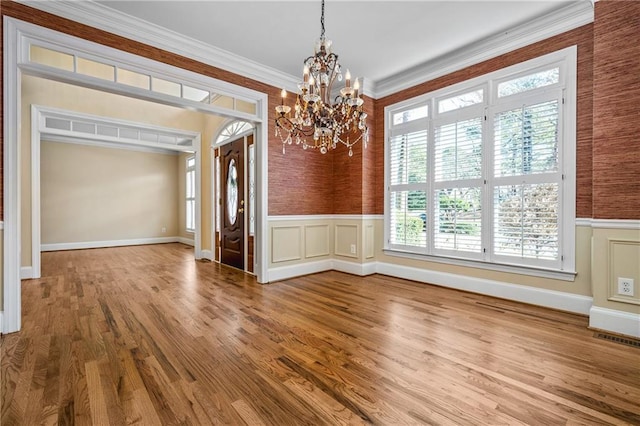 unfurnished dining area featuring hardwood / wood-style flooring, an inviting chandelier, and ornamental molding