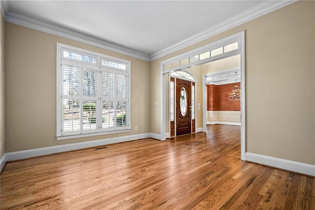 entrance foyer with light hardwood / wood-style flooring, an inviting chandelier, and ornamental molding