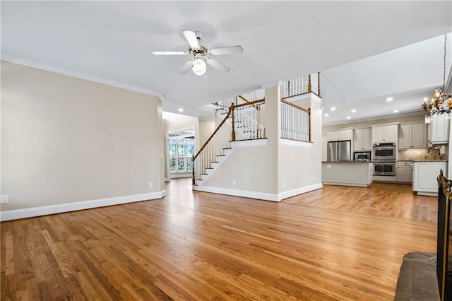 unfurnished living room with ceiling fan with notable chandelier, light hardwood / wood-style floors, ornamental molding, and sink