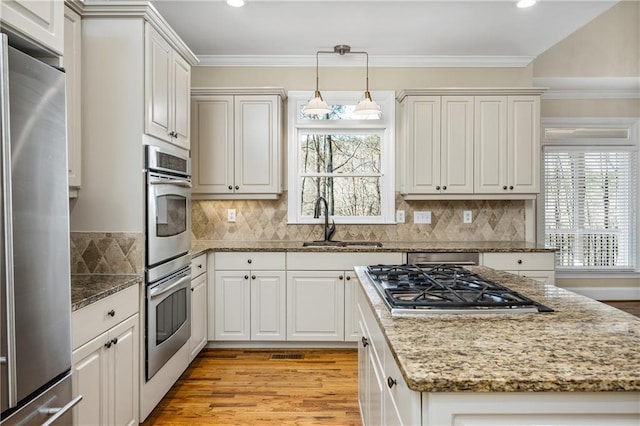 kitchen featuring sink, white cabinetry, stainless steel appliances, and hanging light fixtures