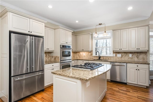 kitchen with stainless steel appliances, crown molding, sink, pendant lighting, and a center island