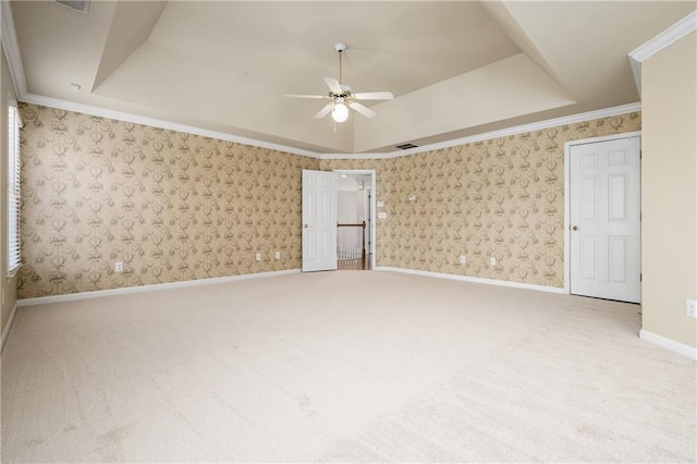 unfurnished bedroom featuring carpet flooring, ceiling fan, ornamental molding, and a tray ceiling