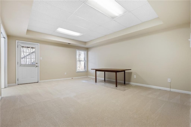 basement featuring a paneled ceiling, light carpet, and a healthy amount of sunlight