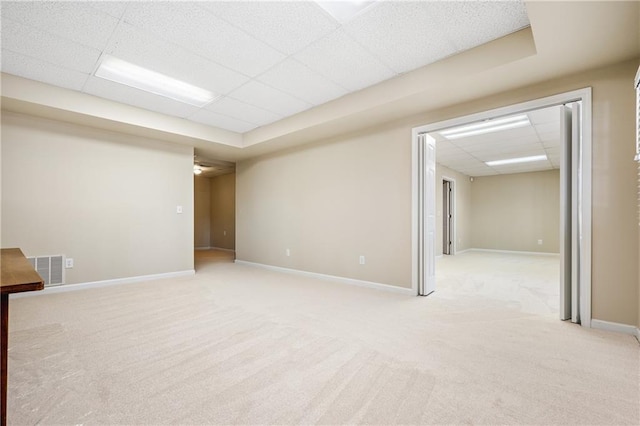 basement featuring light carpet and a paneled ceiling