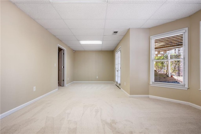 carpeted spare room with a drop ceiling