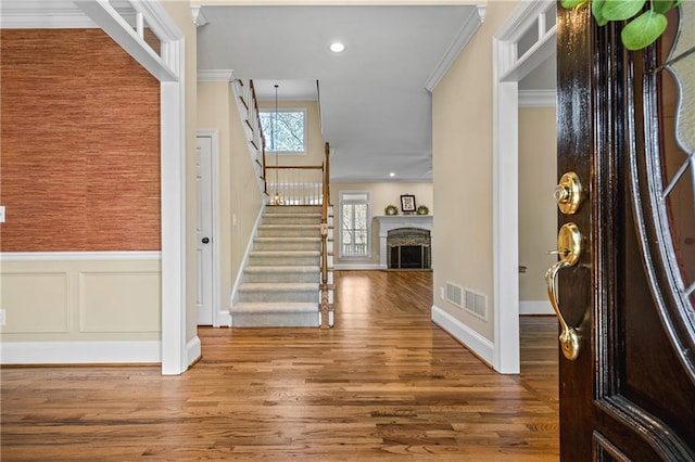 entryway with wood-type flooring and ornamental molding