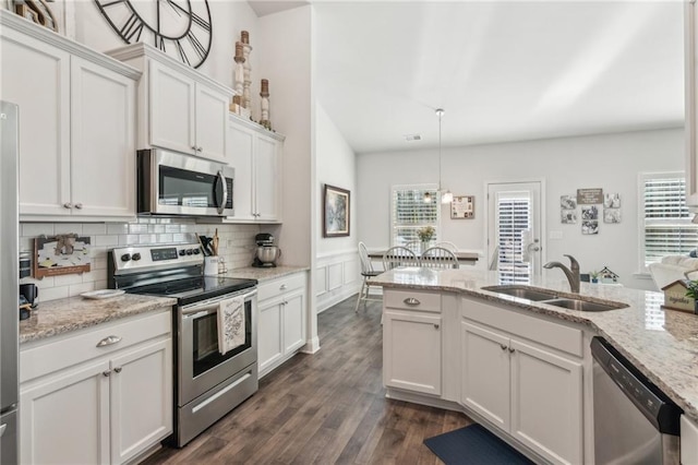 kitchen featuring a wainscoted wall, a sink, dark wood-type flooring, appliances with stainless steel finishes, and white cabinetry