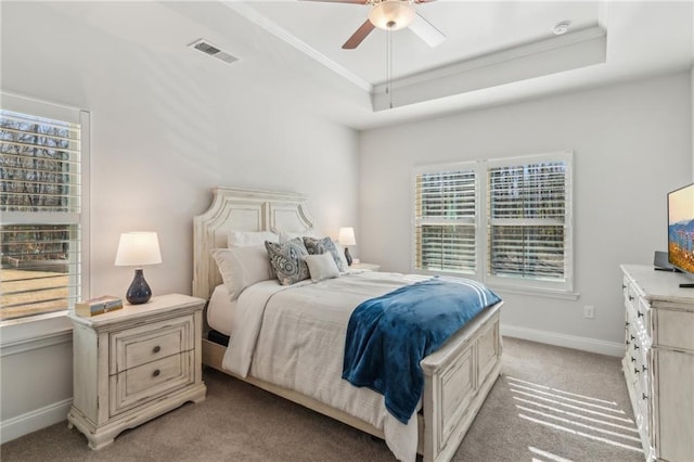 bedroom with visible vents, crown molding, baseboards, light colored carpet, and a raised ceiling