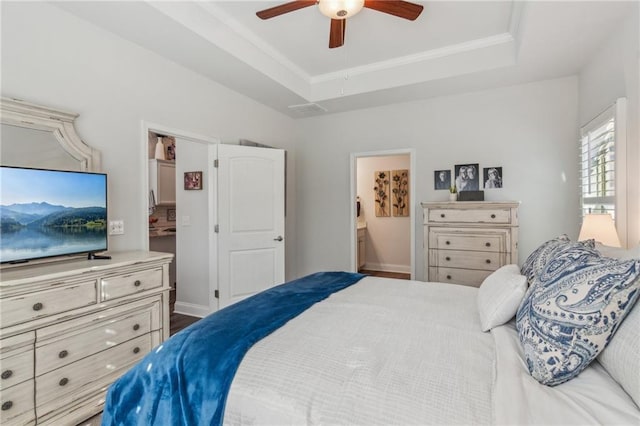 bedroom featuring a tray ceiling, a ceiling fan, ensuite bathroom, and crown molding