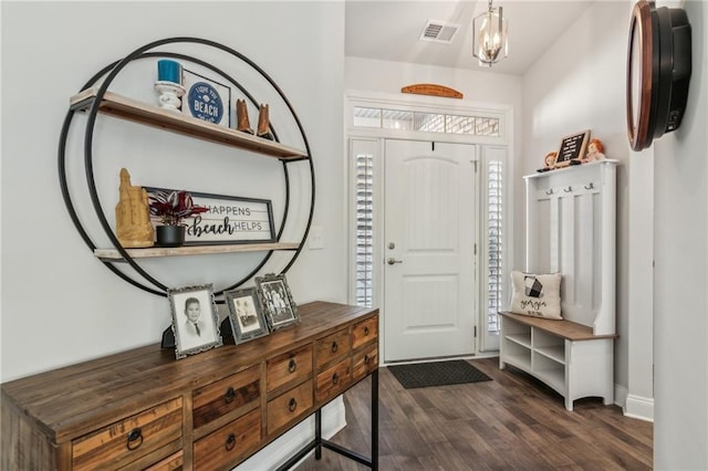 foyer with dark wood finished floors, visible vents, and an inviting chandelier