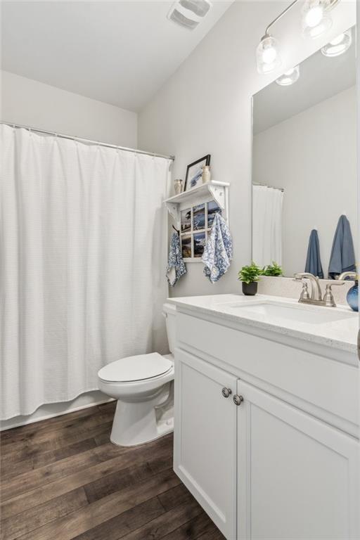 full bathroom featuring visible vents, toilet, wood finished floors, a shower with shower curtain, and vanity