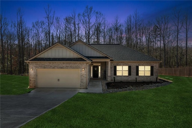 view of front of property featuring brick siding, an attached garage, a shingled roof, a front yard, and driveway